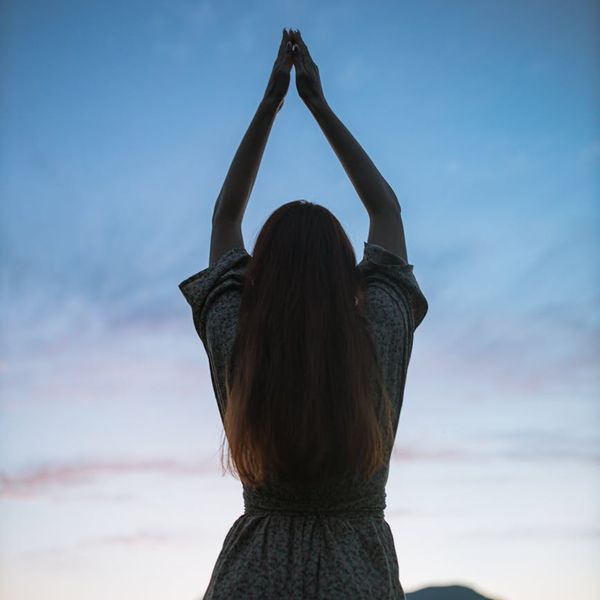 Silhouette of a person in a deep stretch yoga pose.