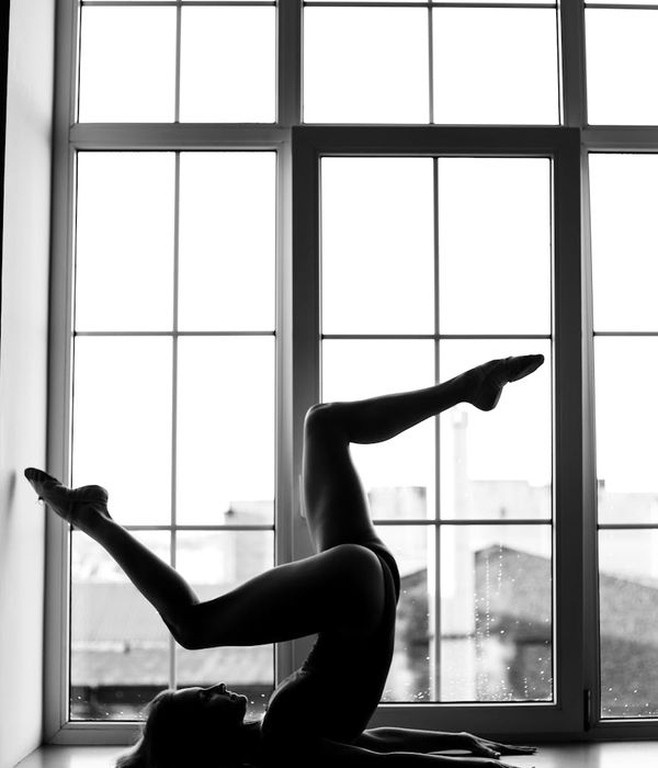 Woman in a calming yoga posture with a warm yellow light effect.